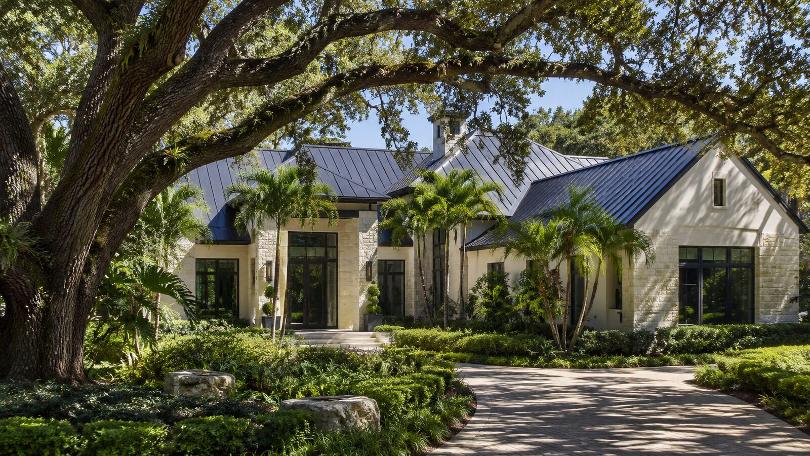 Standing seam metal roof on a Pinecrest estate framed by mature oak canopy
